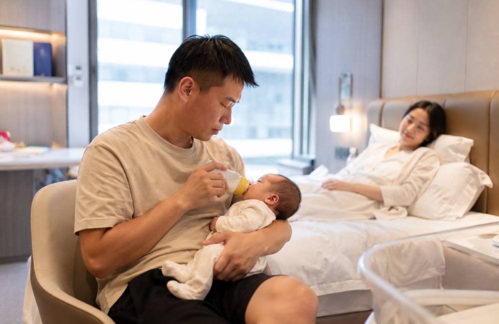 Jeune papa chinois donne le biberon &agrave; son enfant